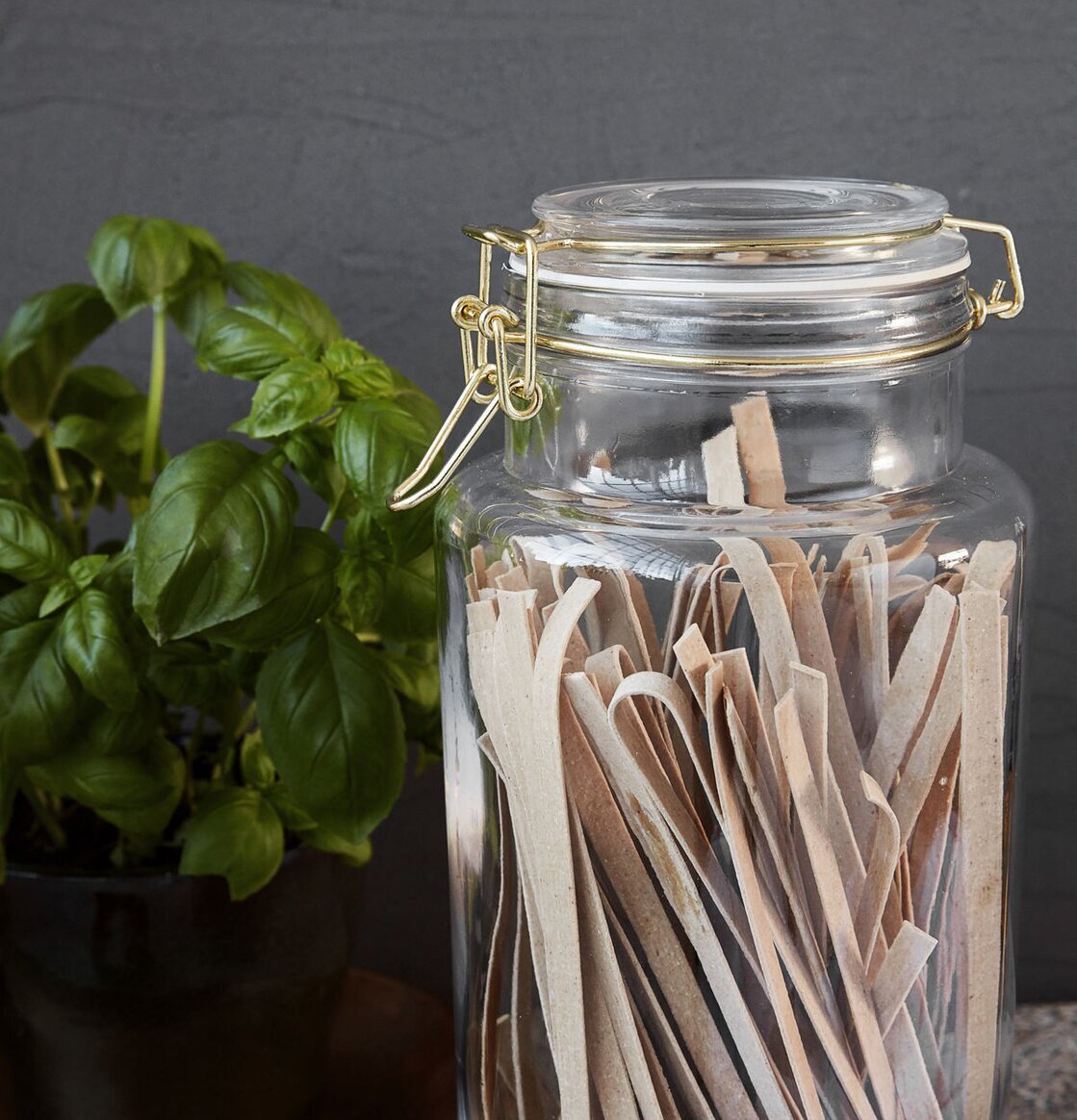 Bild av glasburk med pasta och basilika i köksmiljö