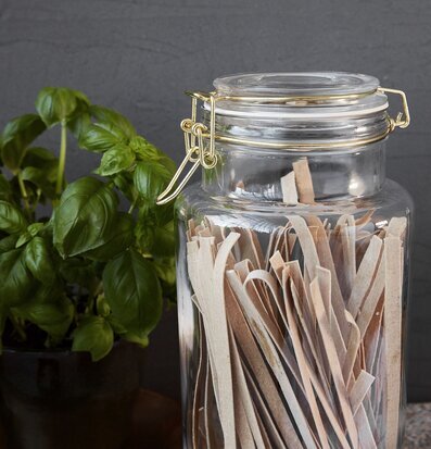 Bild av glasburk med pasta och basilika i köksmiljö