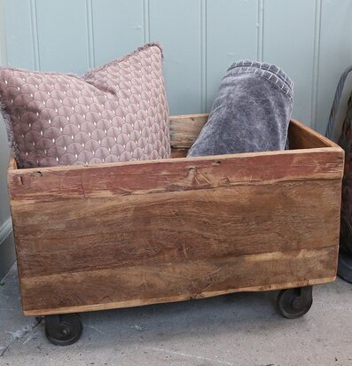 Bild av rustik trälåda på hjul med kuddar och lykta