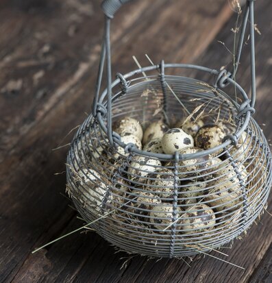 Foto av en rustik trådkorg med ägg på träbord