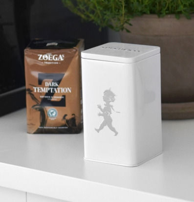 Foto av stilren kaffeburk och växt i harmonisk miljö