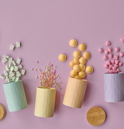 Foto av färgglada keramiska förvaringsburkar på rosa