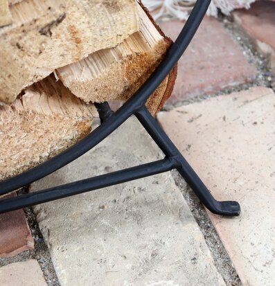 Bild av robust förvaringsställ i metall med ved på tegelgolv