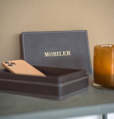 Bild på elegant konstläderlåda för mobilförvaring och glas